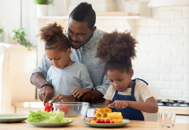 Happy biracial family involved in cooking tasty vegetarian dishes.